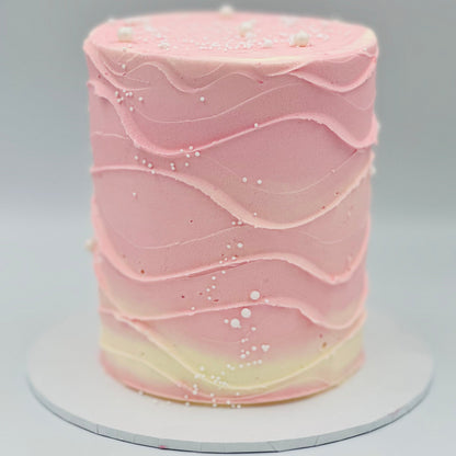 Full view of a baby pink and white wave-effect mud or sponge cake in Adelaide, featuring soft pastel colours and flowing decorative details.
