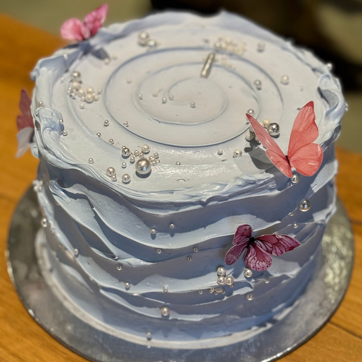 top view of a baby blue and white birthday cake in Adelaide, showcasing its modern wave-effect design and pastel colour palette.